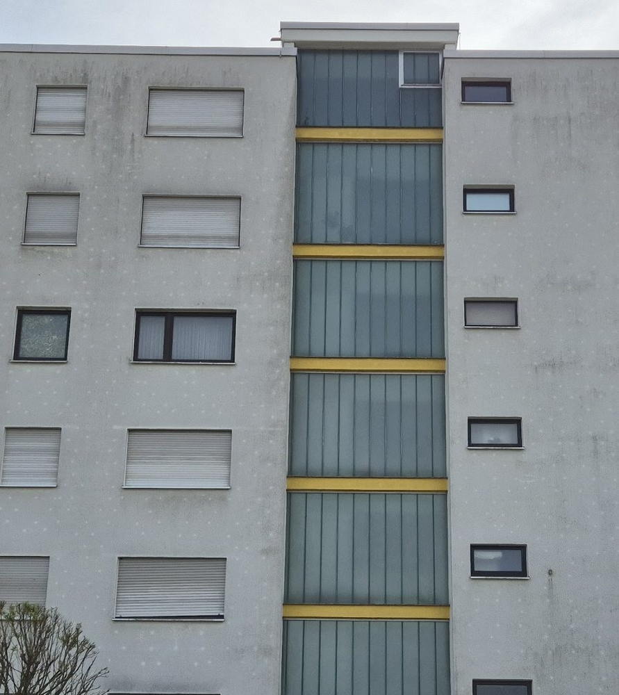 Sechsgeschossige Wohnanlage mit grau verschmutzter Fassade vor der Reinigung